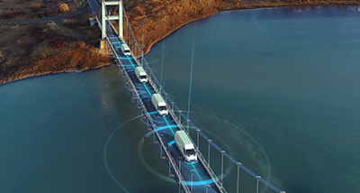 suspension bridge over water with four trucks crossing and digital signal overlays for advanced technology and connectivity