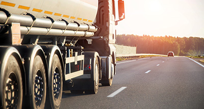oil tanker truck driving on a highway under sunset with eight wheels visible