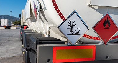 hazardous materials transportation truck featuring warning signs for chemicals and environmental protection