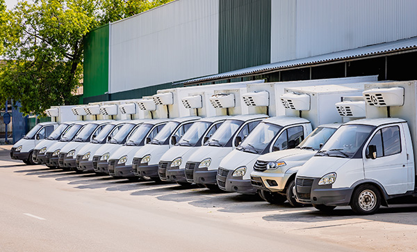 a line of refrigerated delivery vans parked neatly on a commercial street 4 efficient vehicles are visible in the image