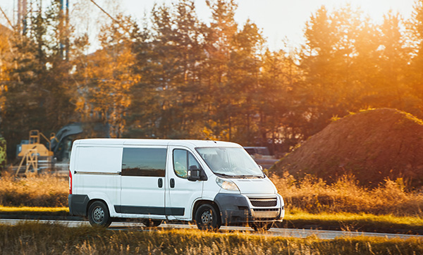 white delivery van driving on rural road with sunset lighting and trees in background showcasing transportation options 2